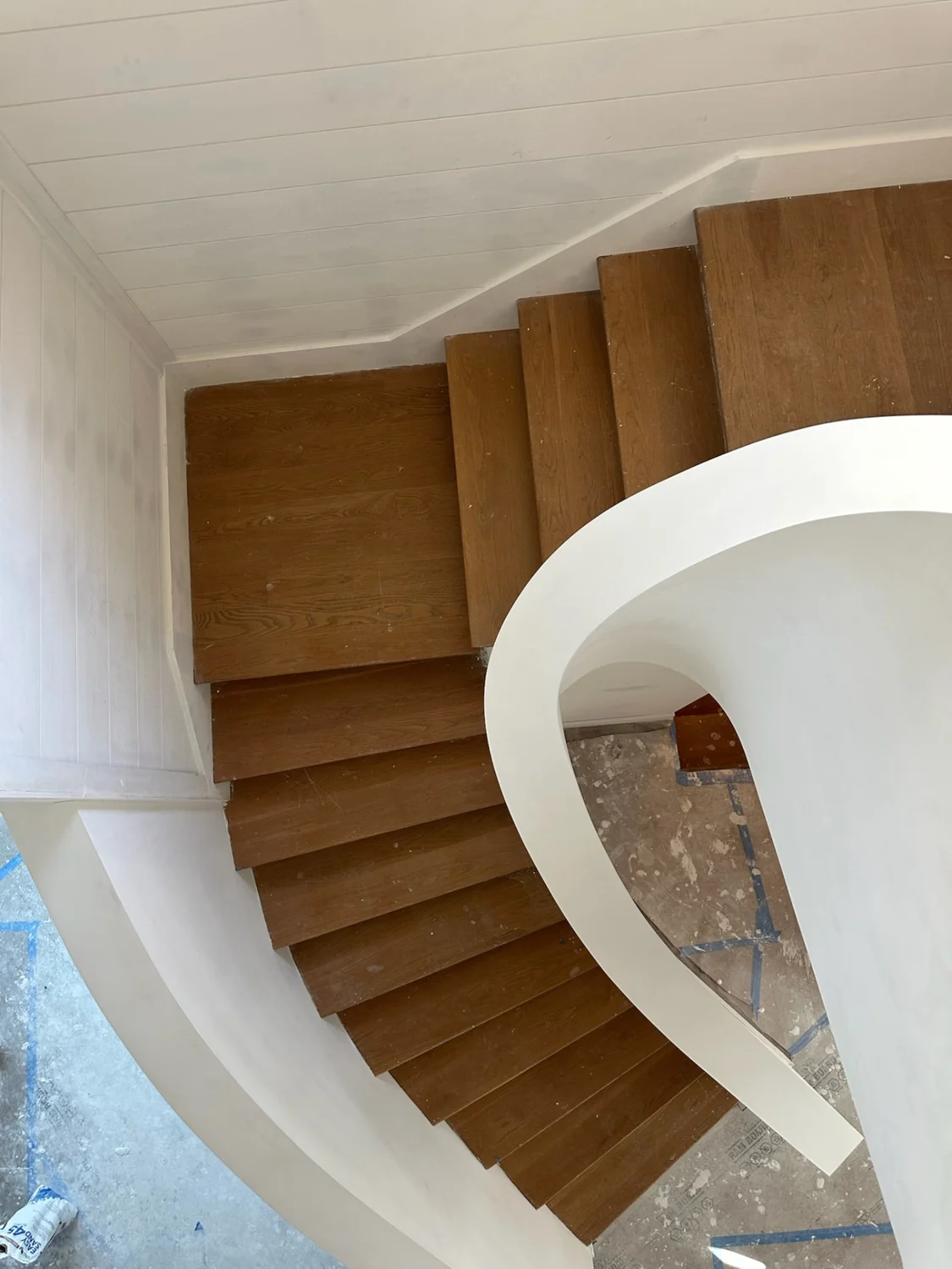 Top-down detail of the repaired spiral staircase drywall edge alongside wooden steps in Sewall's Point, Florida