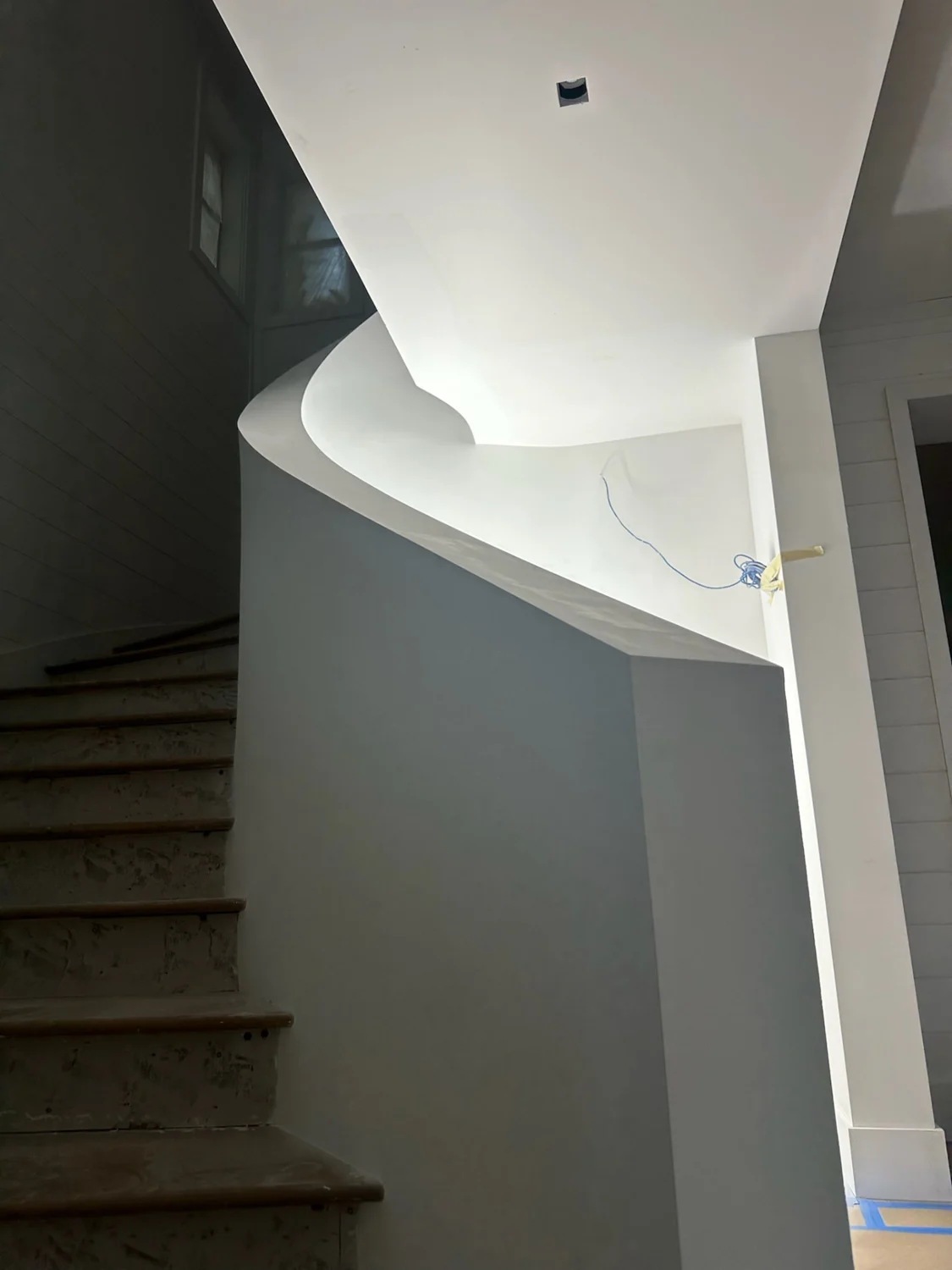View from below of the refined curved staircase wall and crisp drywall edge in Sewall's Point, Florida