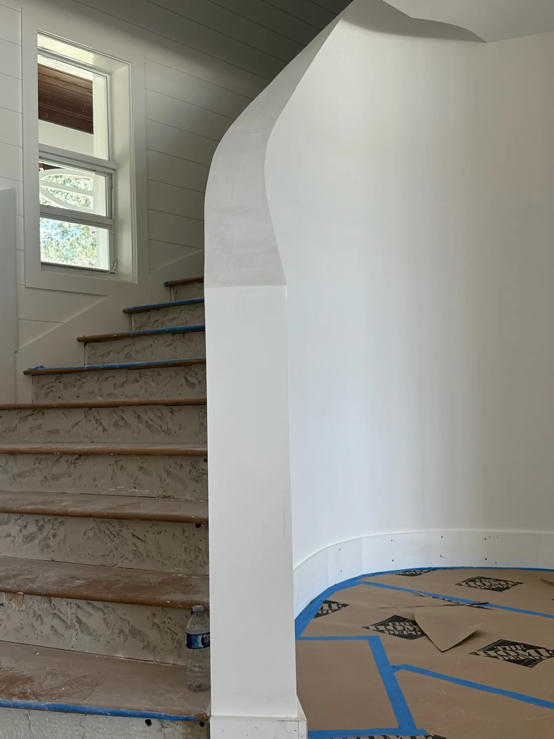 Completed drywall repair along the curved staircase wall beside wooden stair treads in Sewall's Point, FL