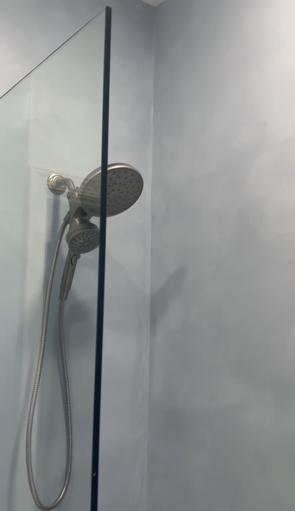 Tadelakt plaster shower wall behind glass panel and shower head, Stuart FL